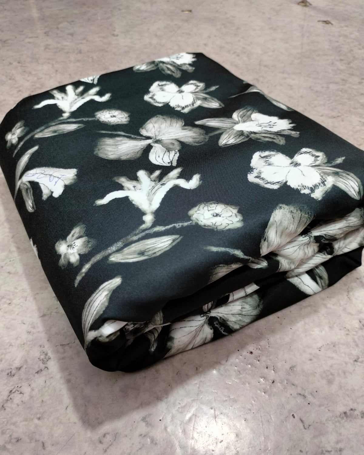 Black floral micro crepe dress material folded into a cut piece