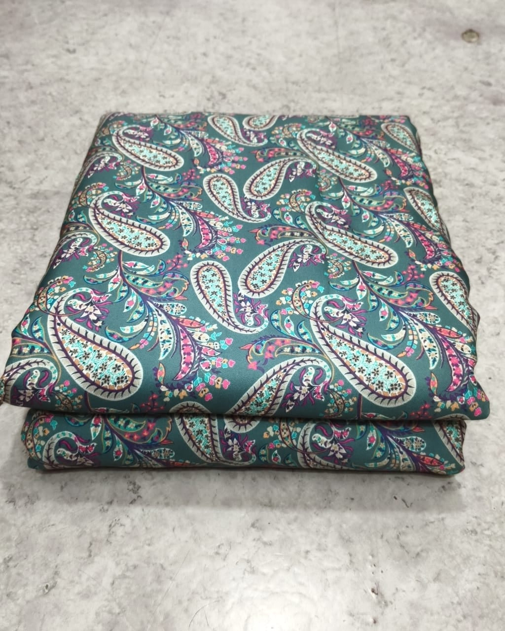 Teal paisley moss dress material folded into a cut piece