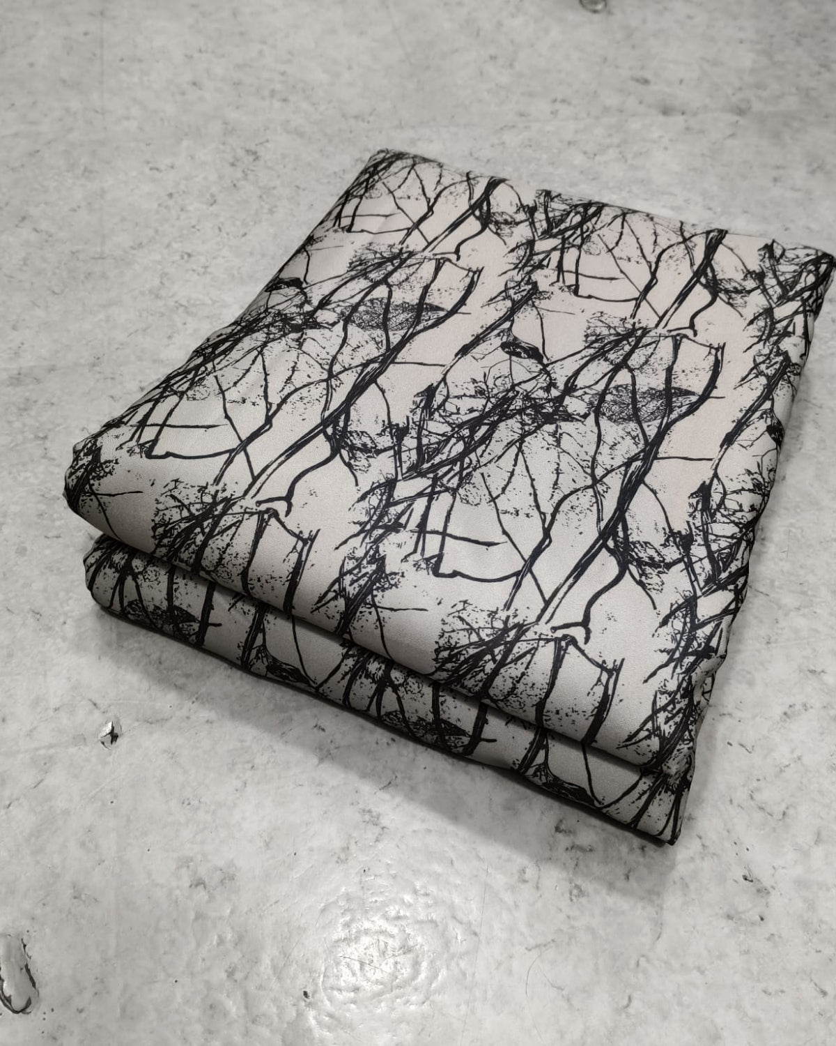 Cream and black branch print moss fabric shown full width