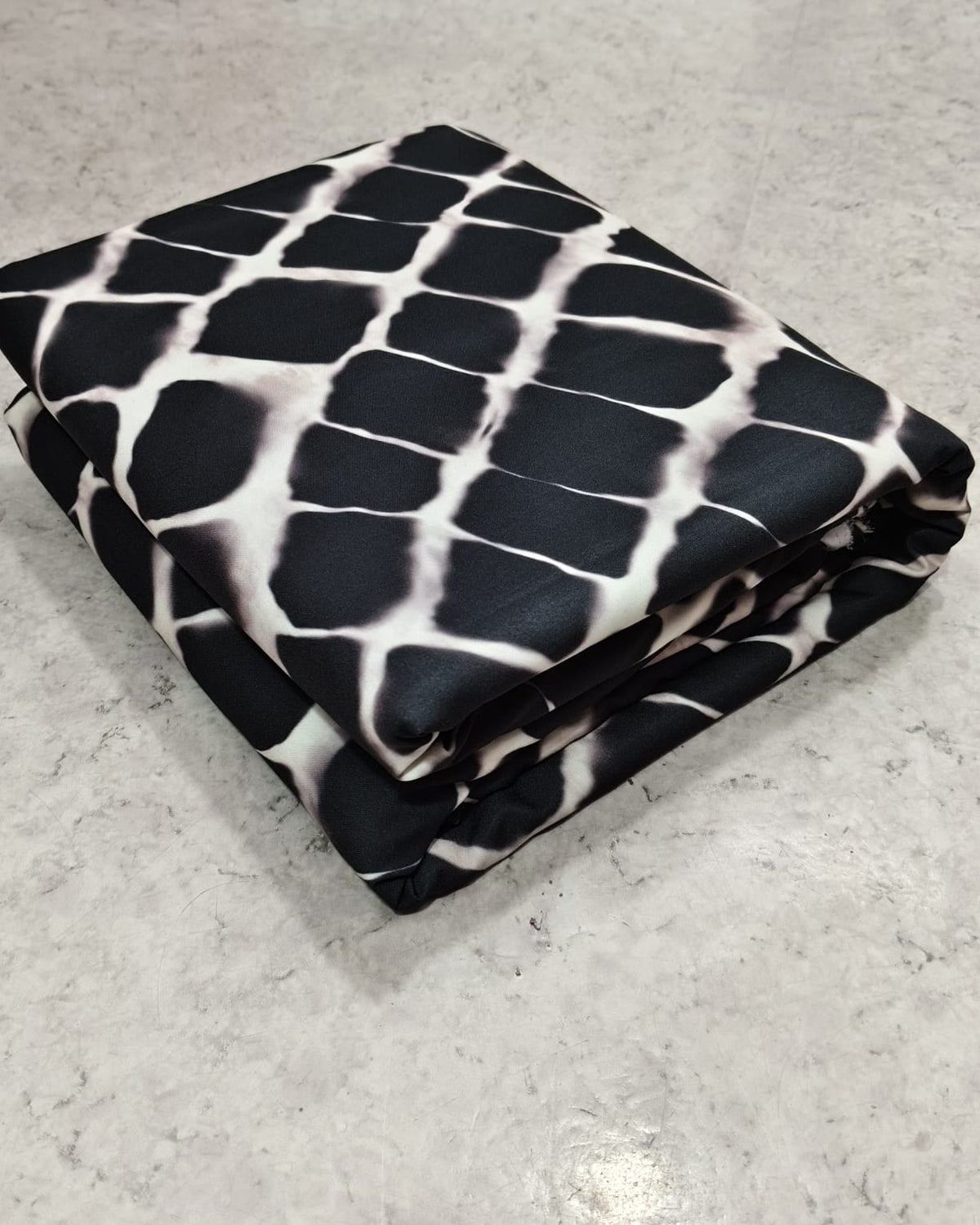 Geometric printed micro crepe dress material folded into a cut piece