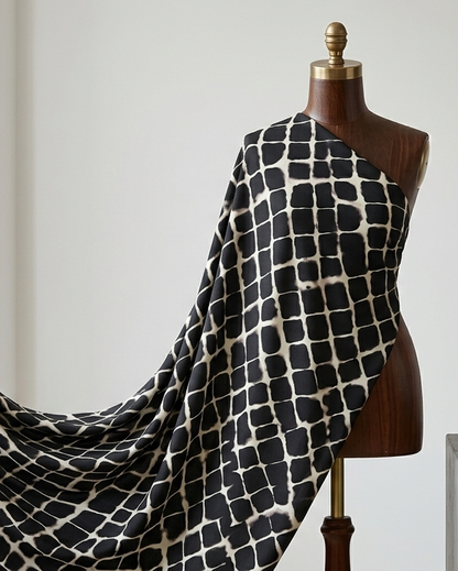 Black and white geometric grid print on micro crepe dress material, laid flat