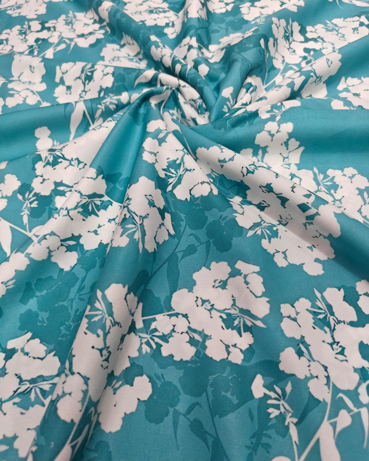 Teal and white blossom micro crepe dress material folded into a cut piece